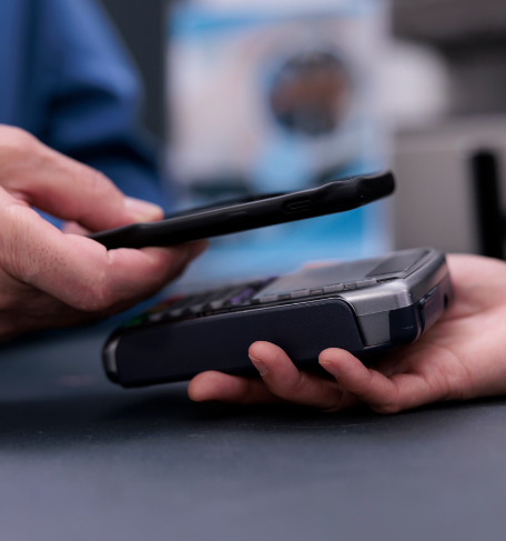 Close-up of person using card reading machine to scan phone