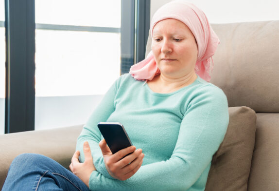 Woman with cancer looking at phone while getting treatment