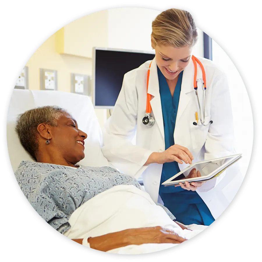 Patient in hospital bed with doctor at side with tablet