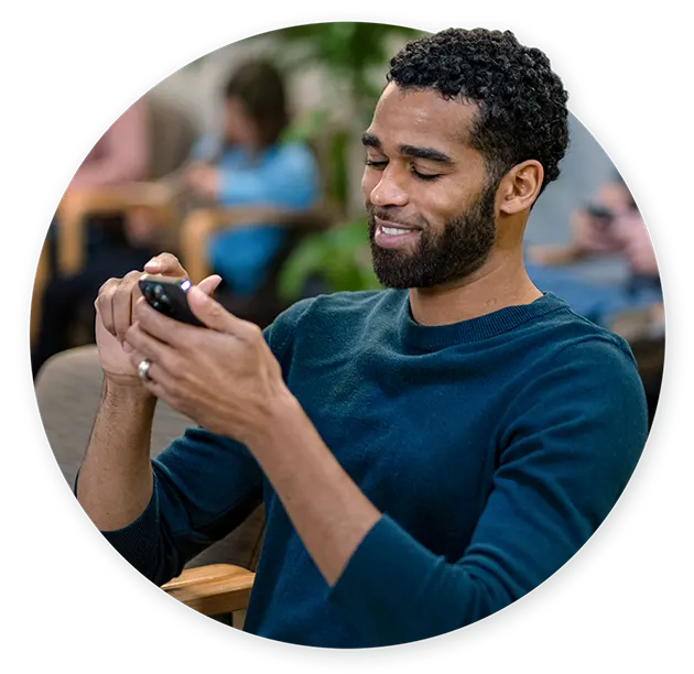 Male patient in waiting room scrolling on mobile phone